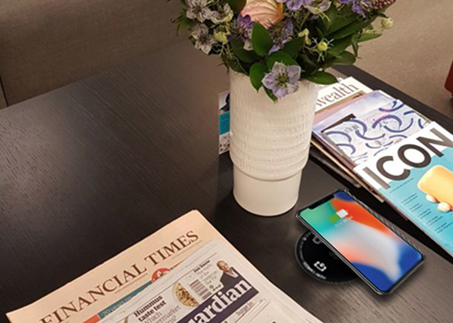 Close-up of iPhone on charger on hotel style table_